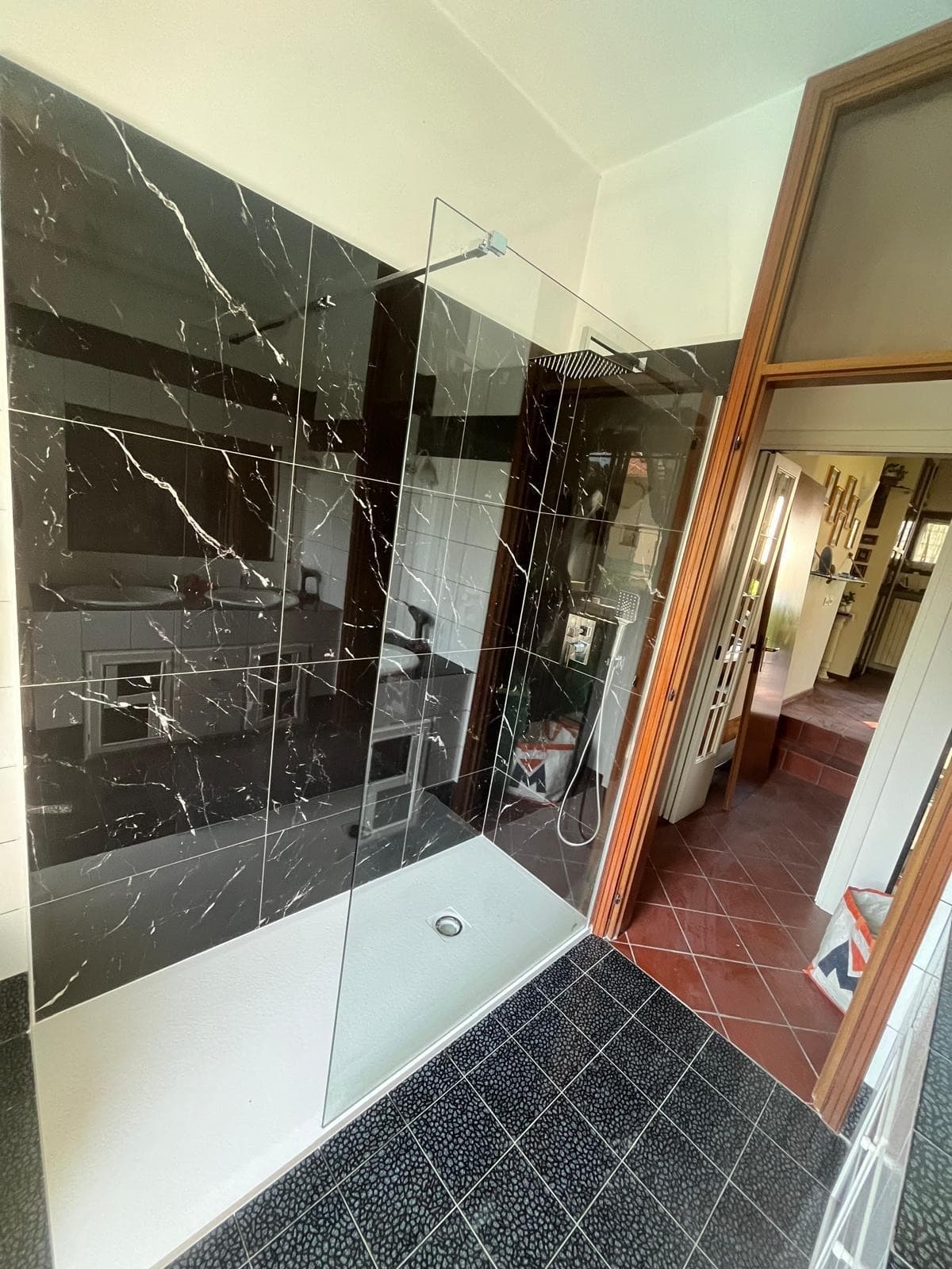 Doccia walk-in con pareti effetto marmo nero e parete in cristallo